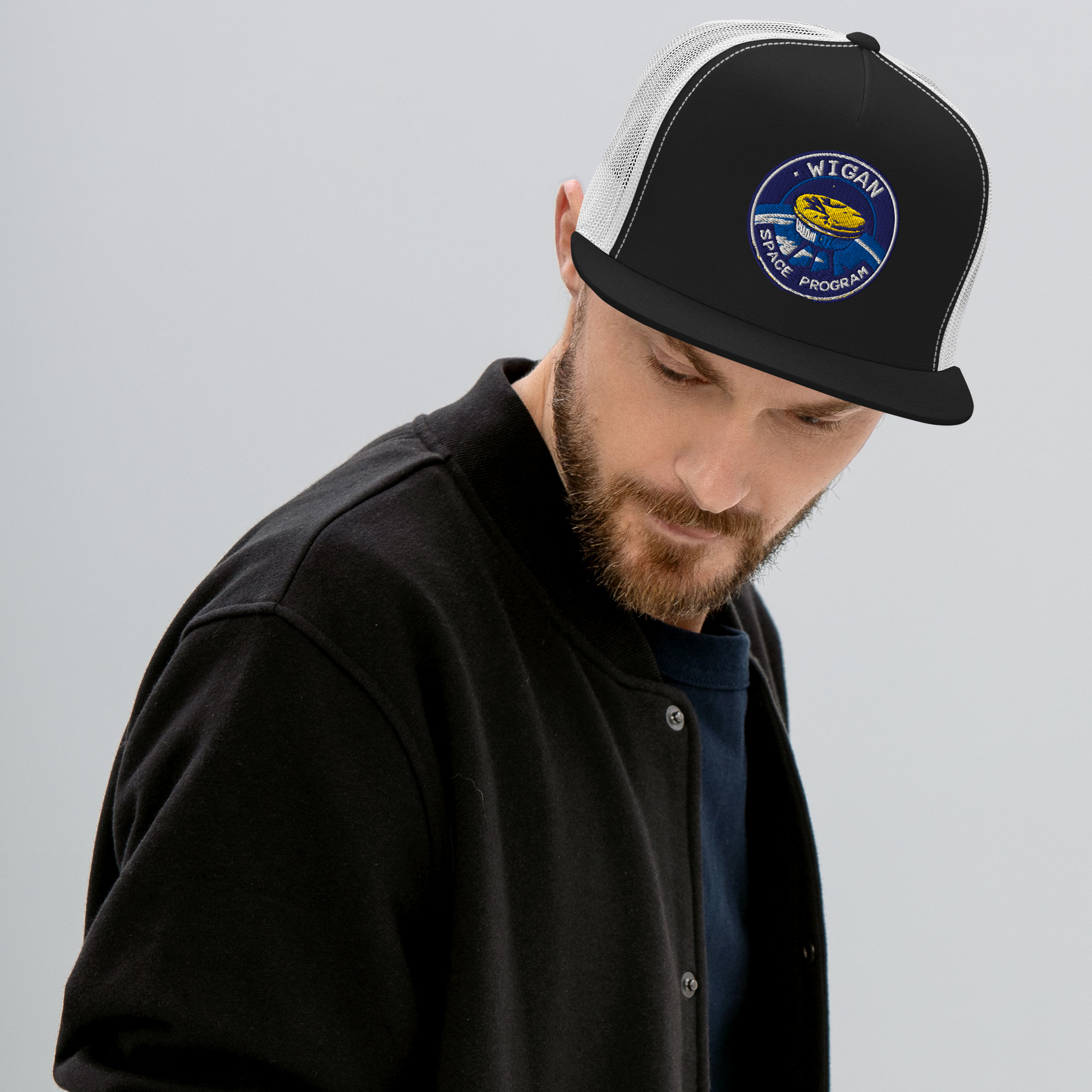 Man wearing a black cap with a logo on a gray background