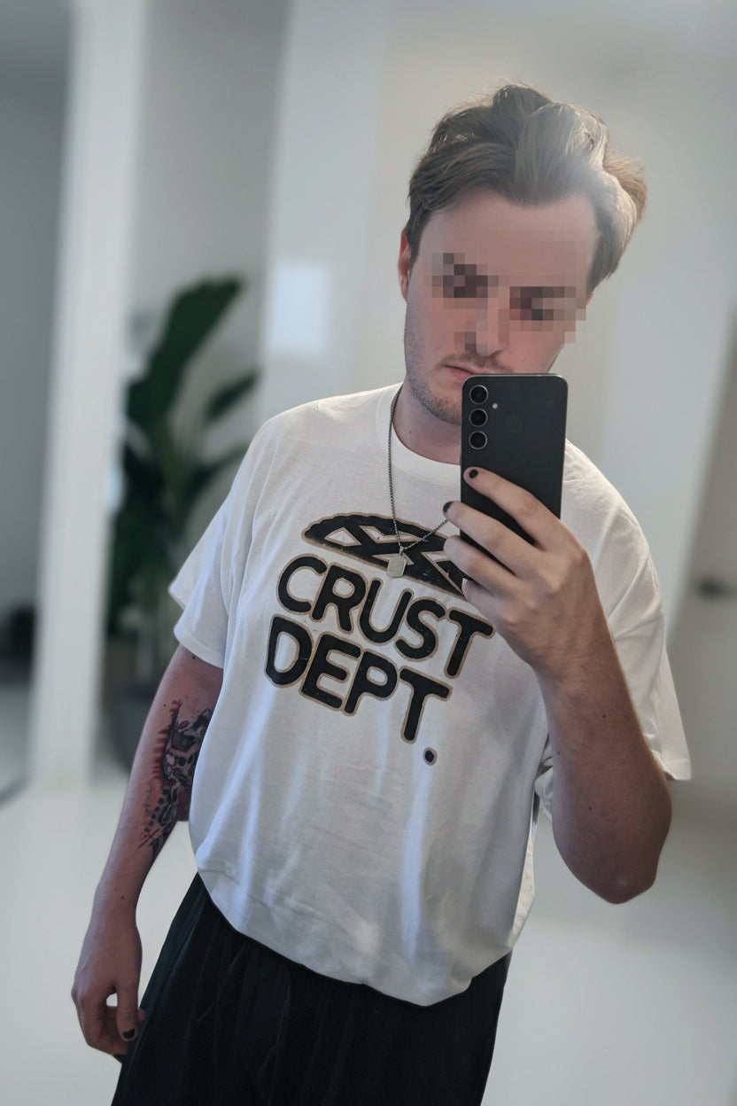 Person wearing a white t-shirt with 'CRUST DEPT.' text, taking a mirror selfie.