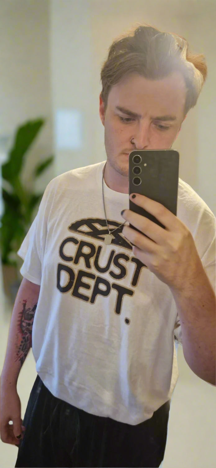 Person wearing a white t-shirt with 'CRUST DEPT.' text, taking a mirror selfie.