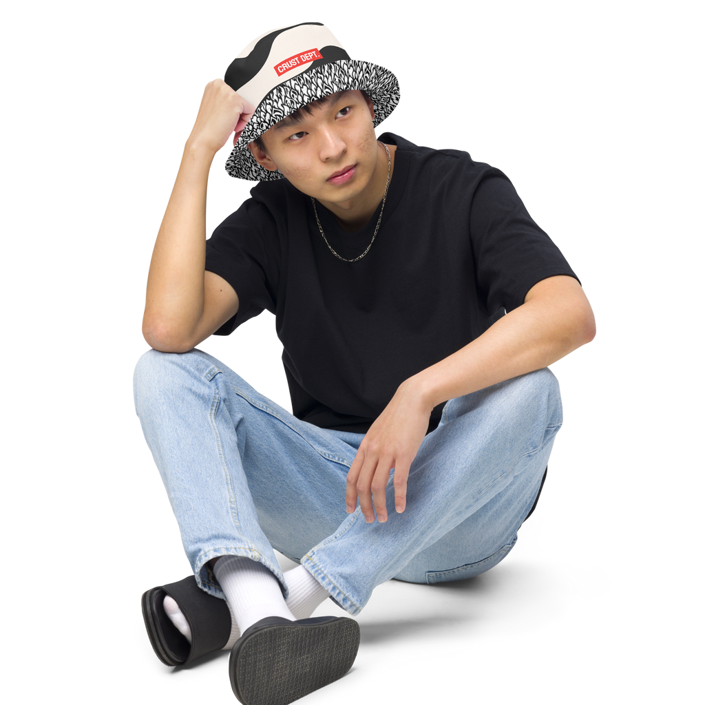 Person wearing a black t-shirt, light blue jeans, and a patterned cap on a white background