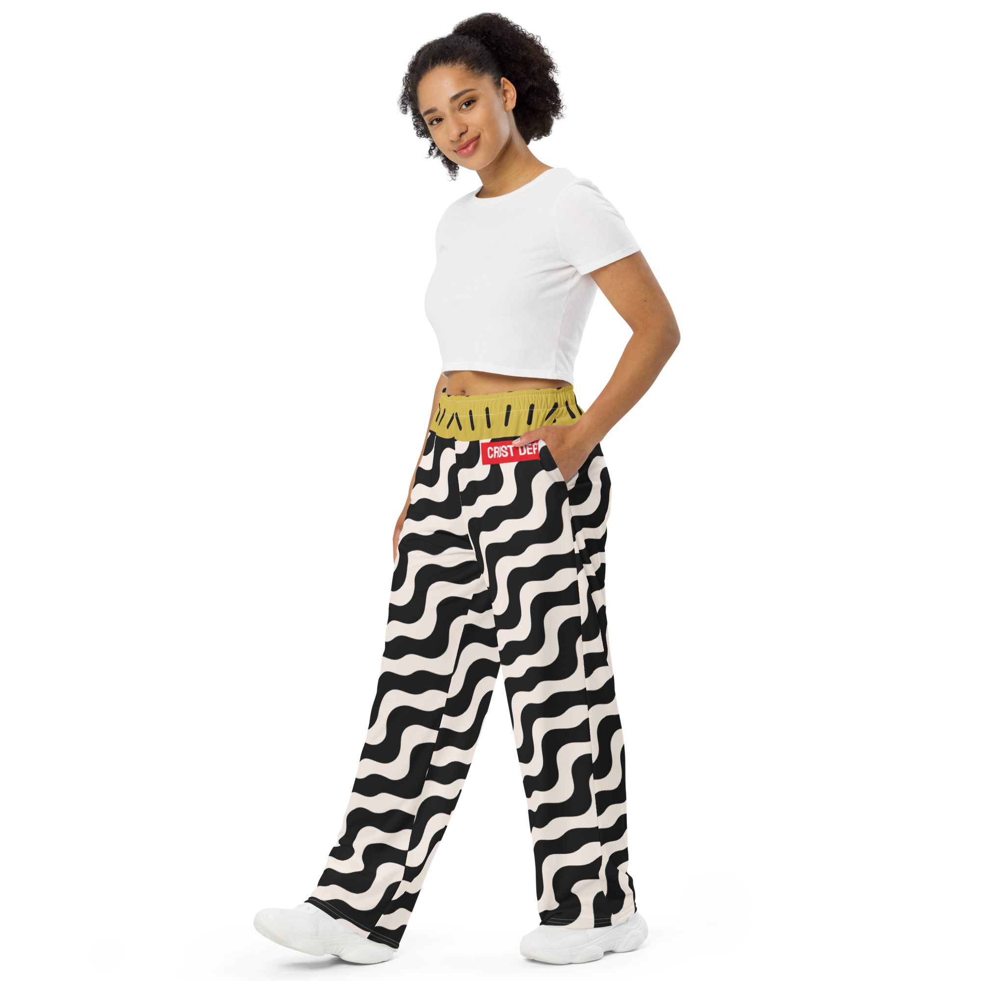 Woman wearing a white crop top and black and white patterned pants on a white background