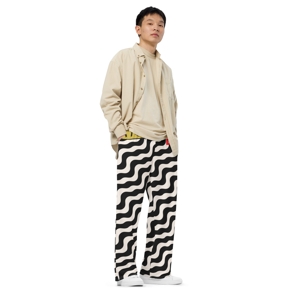 Person wearing a beige shirt and black and white patterned pants on a white background