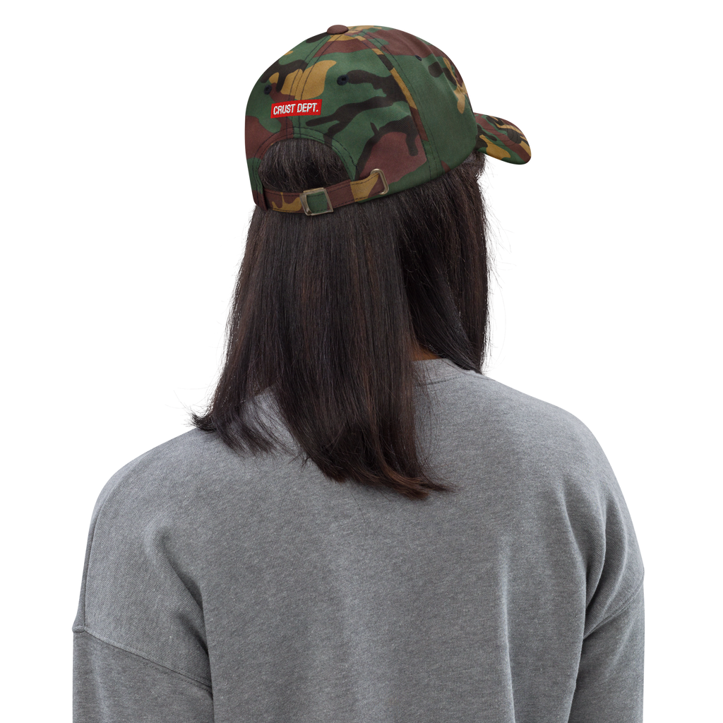 Person wearing a camouflage cap with 'CRUST DEPT.' logo on a white background