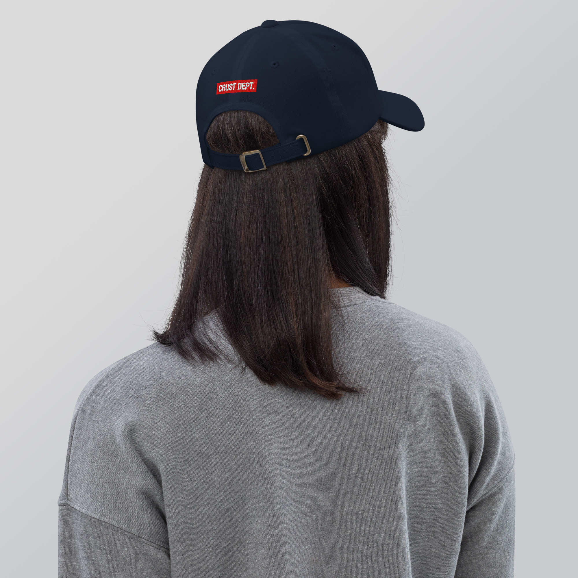 Person wearing a navy cap with a red label on a plain background