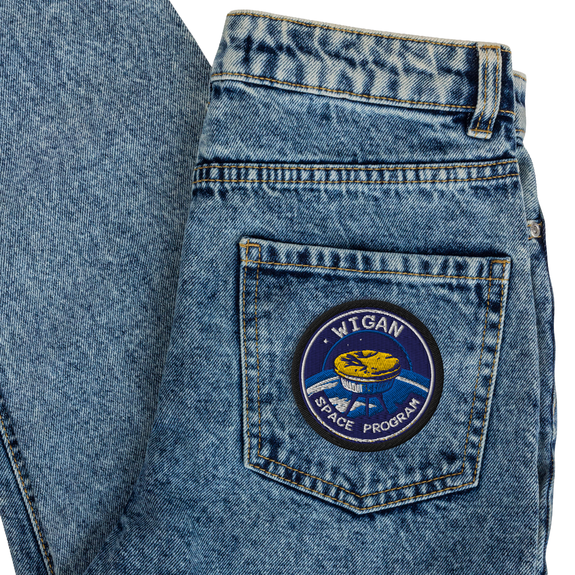Blue denim jeans with a patch on the back pocket featuring 'Wigan Space Program' design.