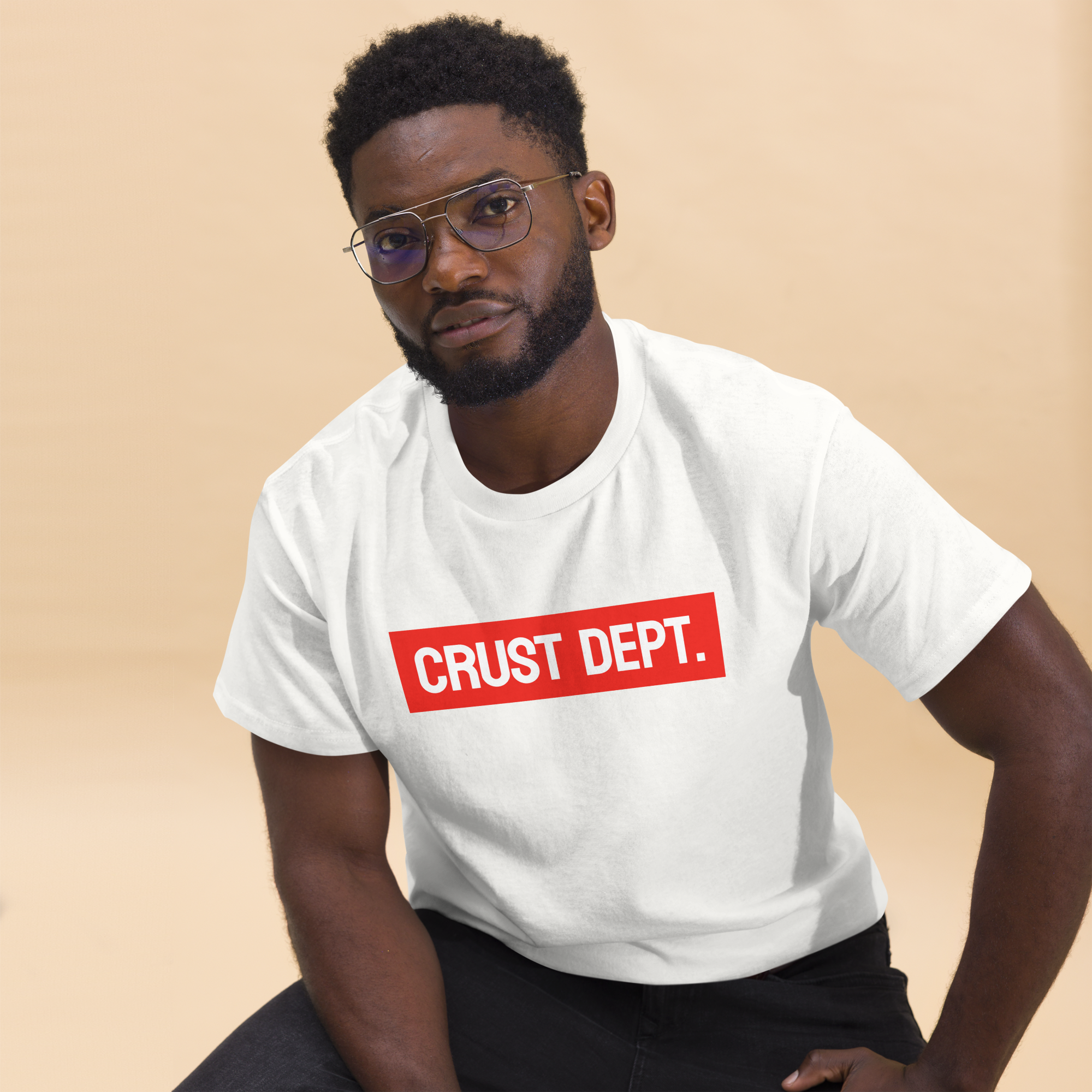Man wearing a white t-shirt with 'CRUST DEPT.' text on a beige background